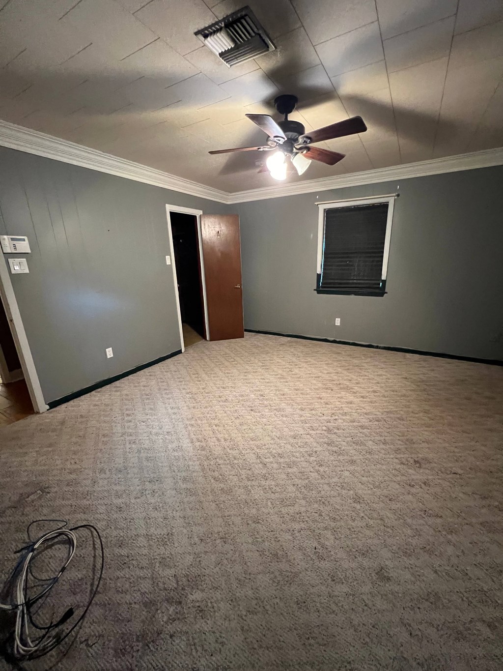 a living room with a ceiling fan and a carpet