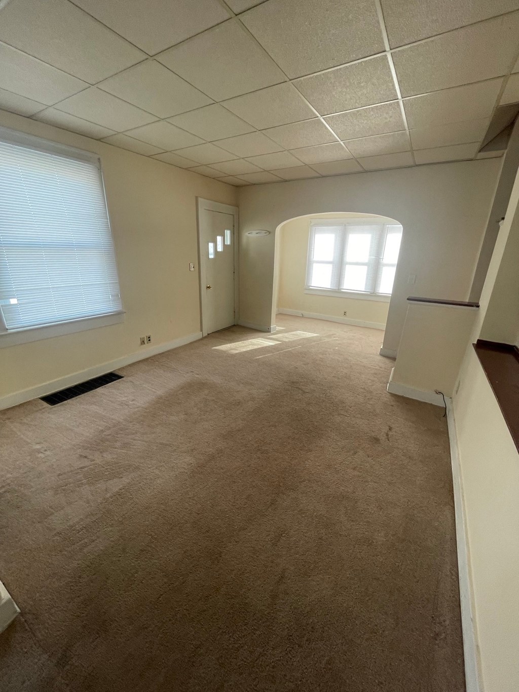 A room with a carpeted floor and a window with blinds.