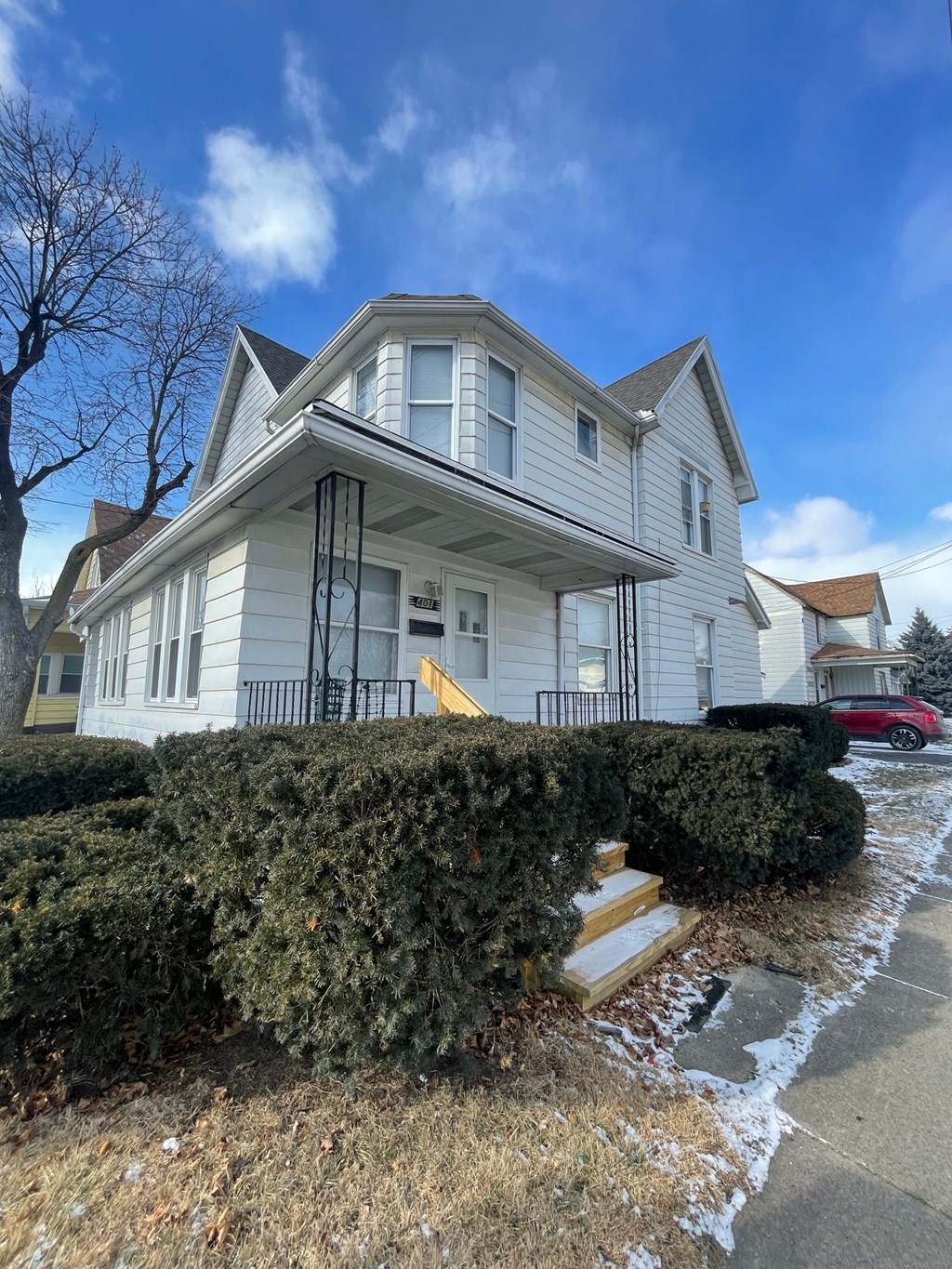 A white house with a red car parked in front.