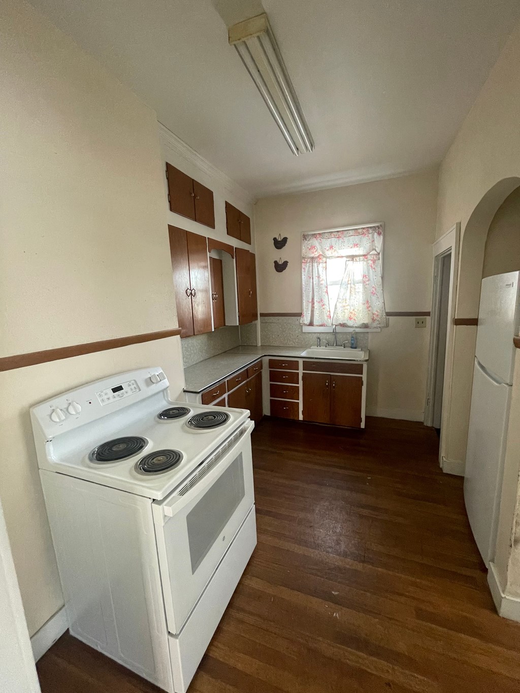A white stove in a kitchen with wooden floors and white walls.