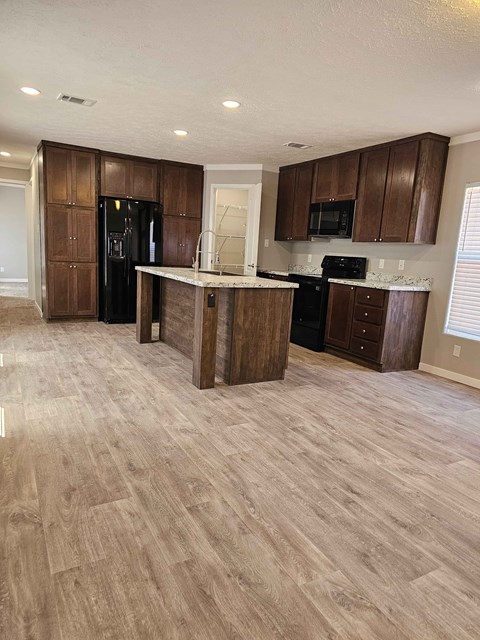 A kitchen with wooden cabinets and a black fridge.