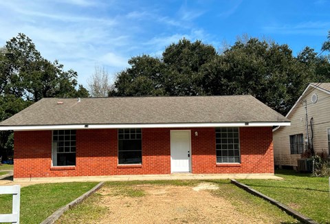 A red brick house with a white door and a white fence.