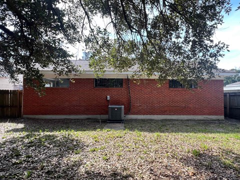 A red brick building with a tree in front.