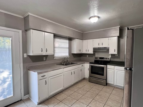 A kitchen with white cabinets and a tiled floor.