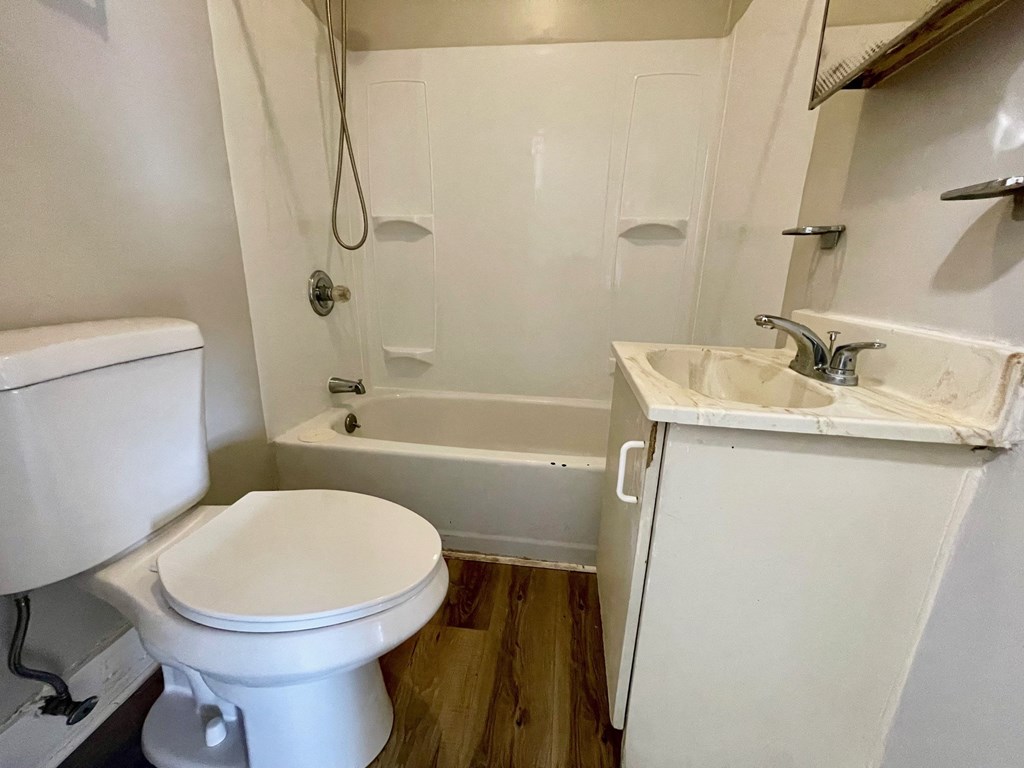 A white toilet sits next to a white sink in a small bathroom.
