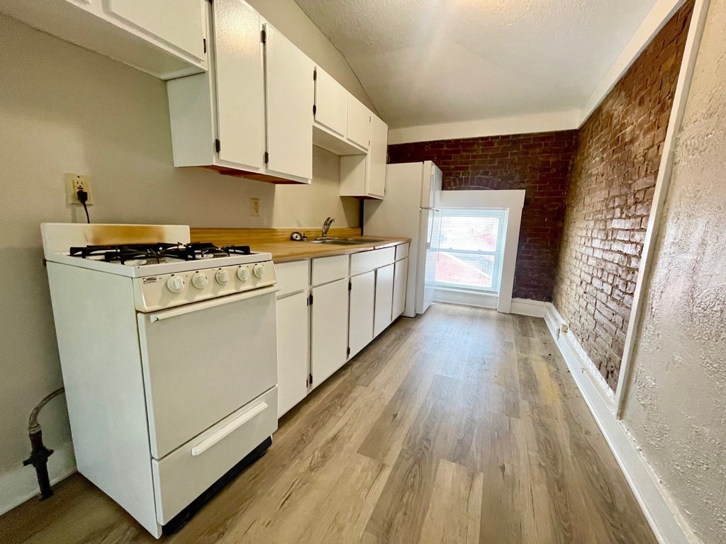 A kitchen with a white gas stove and white cabinets.