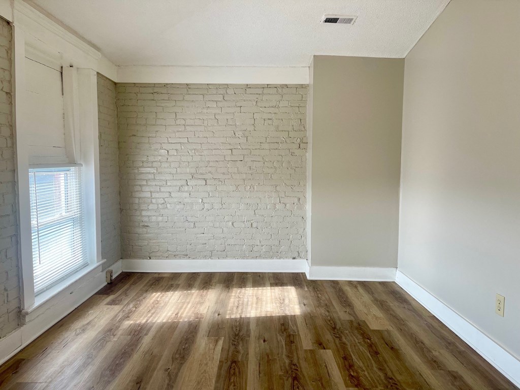 A room with wooden floors and a white brick wall.