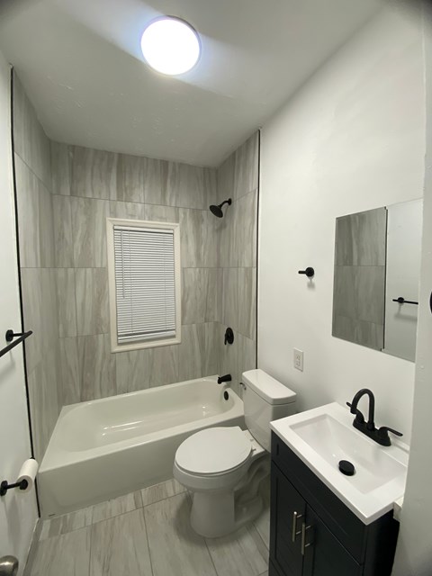 A white toilet sits next to a bathtub in a bathroom.