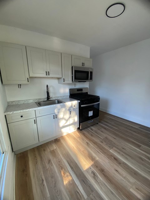 A kitchen with wooden floors and white cabinets.