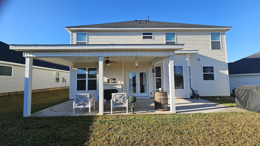 A house with a covered patio and white furniture.