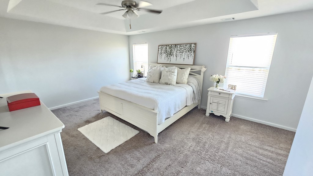 A bedroom with a bed, nightstand, and a ceiling fan.
