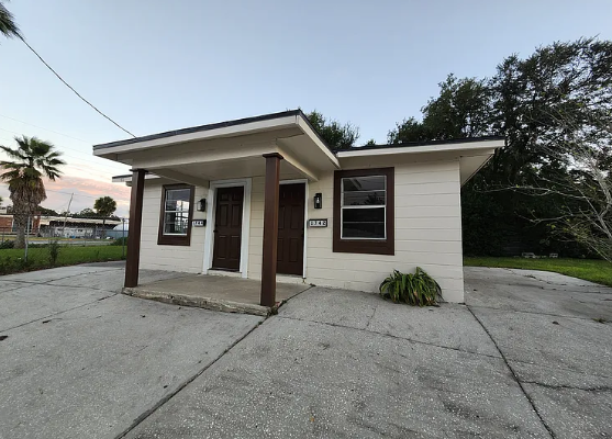 A small white house with a brown door and windows.