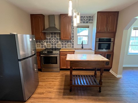 A kitchen with a black fridge and wooden cabinets.