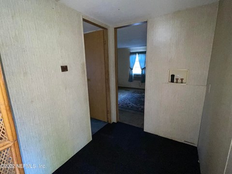 A room with a door leading to a bedroom.