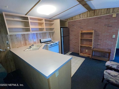 A kitchen area with a refrigerator, sink, and cabinets.
