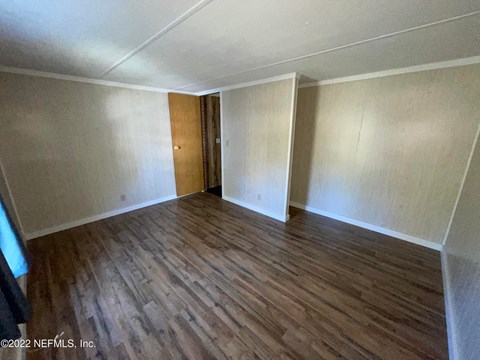 A room with wooden flooring and a door in the middle.