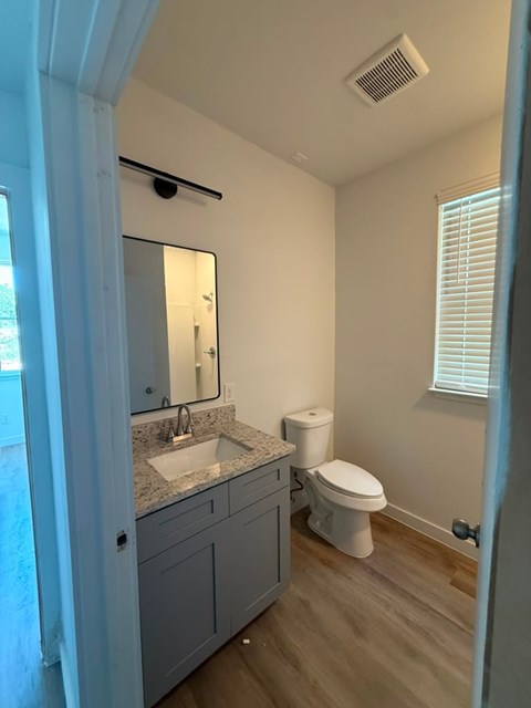 A bathroom with a sink, toilet and mirror.