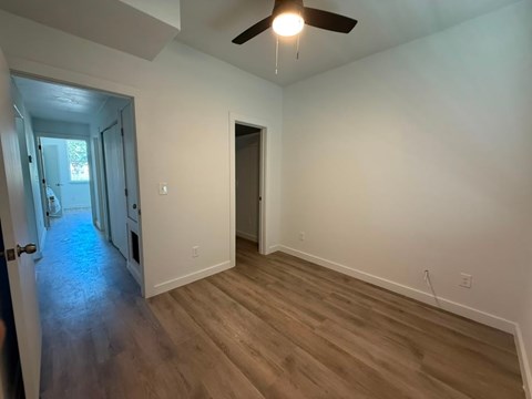 A room with a ceiling fan and wooden flooring.
