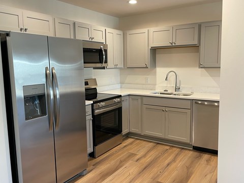A kitchen with a stainless steel refrigerator and wooden floors.