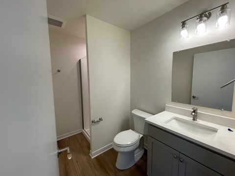 A bathroom with a toilet, sink, and mirror.