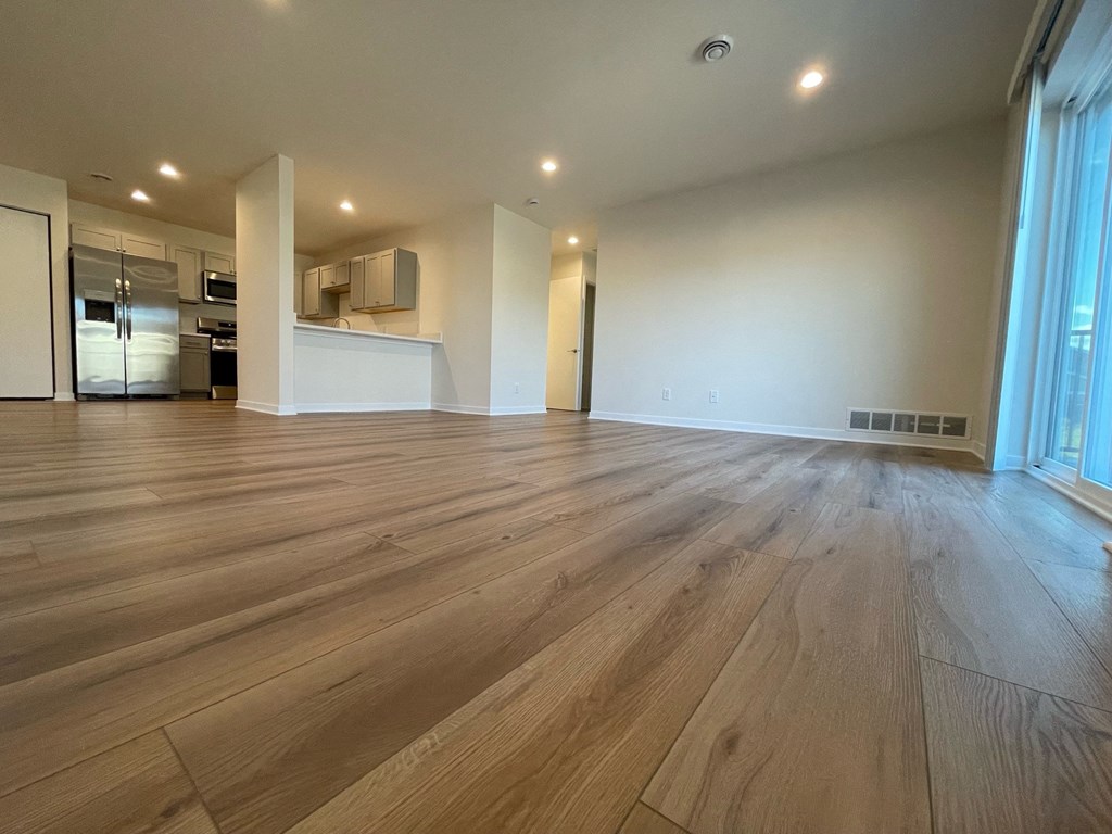 a living room with hardwood floors and a kitchen