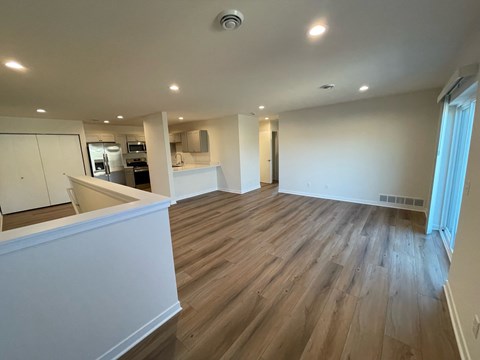 A spacious room with wooden flooring and white walls.