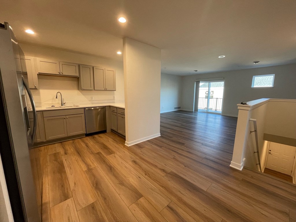 a kitchen and living room with wood flooring in a new home
