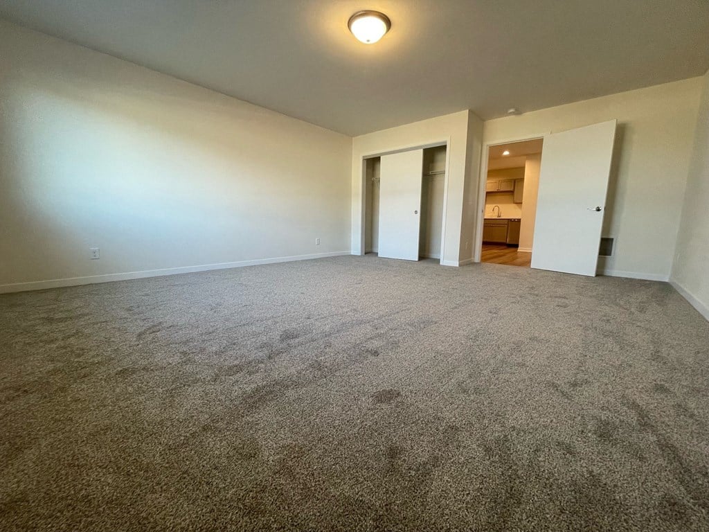 an empty living room with white walls and carpet
