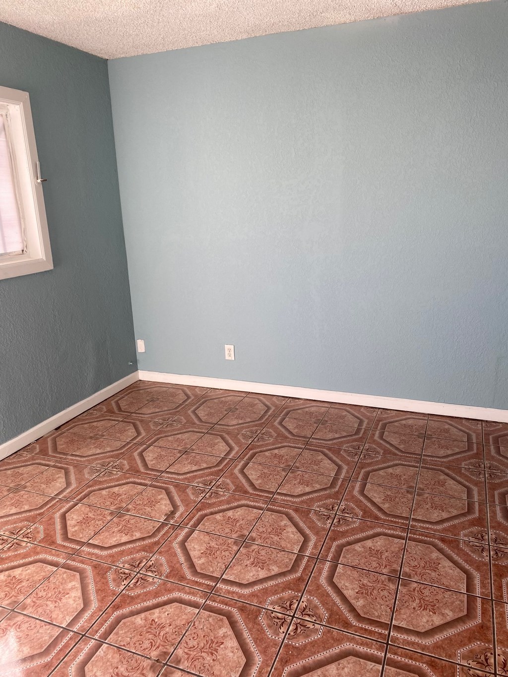 an empty room with blue walls and a brown floor