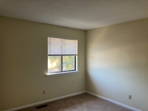 A room with a window and a carpeted floor.