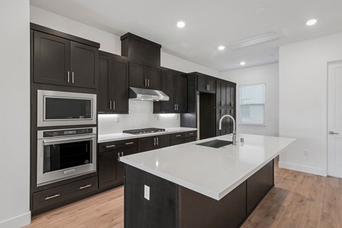 a kitchen with dark cabinets and white counter tops and a large island