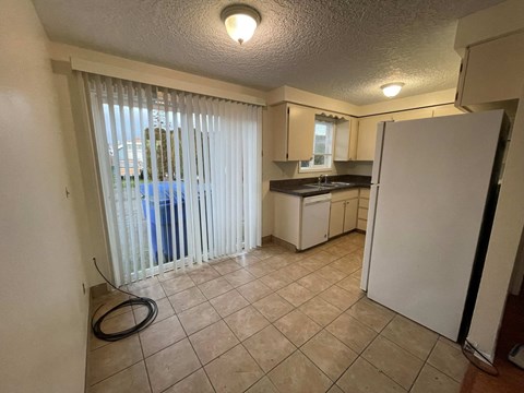 A kitchen with a refrigerator, sink, and cabinets.