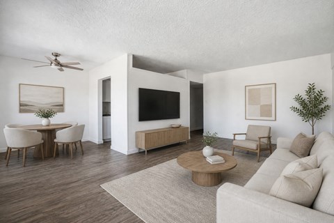 A living room with a white couch, a wooden coffee table, and a television.