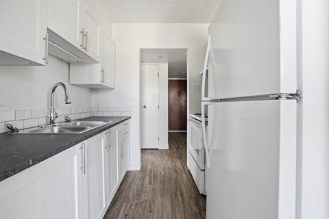 A kitchen with white cabinets and a black counter top.