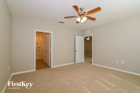 a living room with a ceiling fan and a door to a bathroom