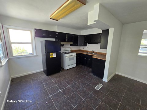 an empty kitchen with black cabinets and white appliances