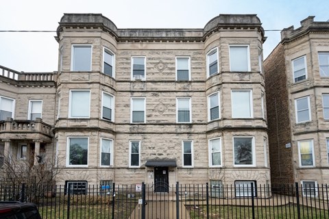 a large stone building with a black door and a fence
