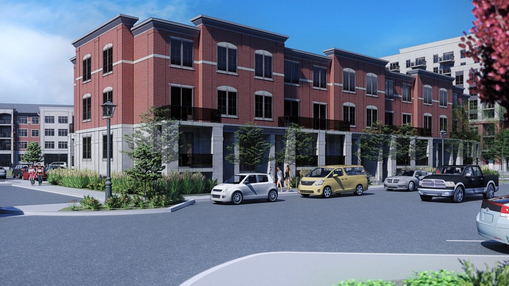 A street view of a red brick building with cars parked in front.