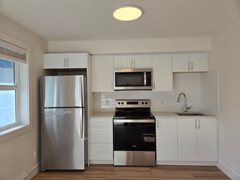 A modern kitchen with stainless steel appliances and white cabinets.