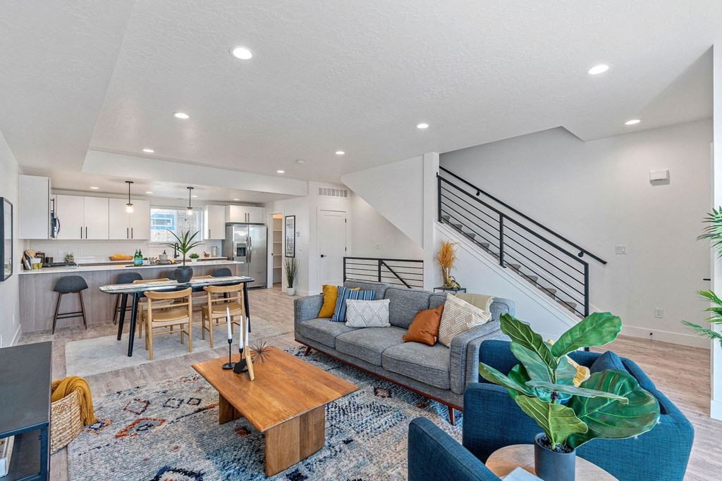 a living room with a couch and a kitchen with a staircase