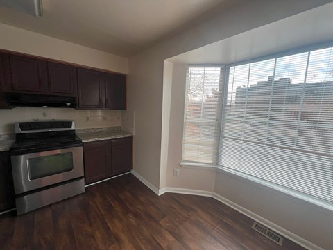 A kitchen with dark wood cabinets and a stainless steel oven.