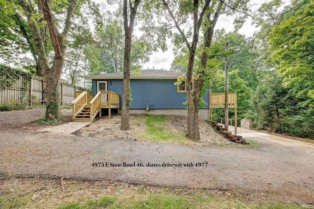 a blue house with a gravel driveway and trees