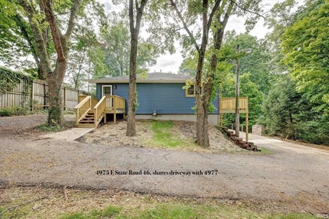 a blue house with a gravel driveway and trees