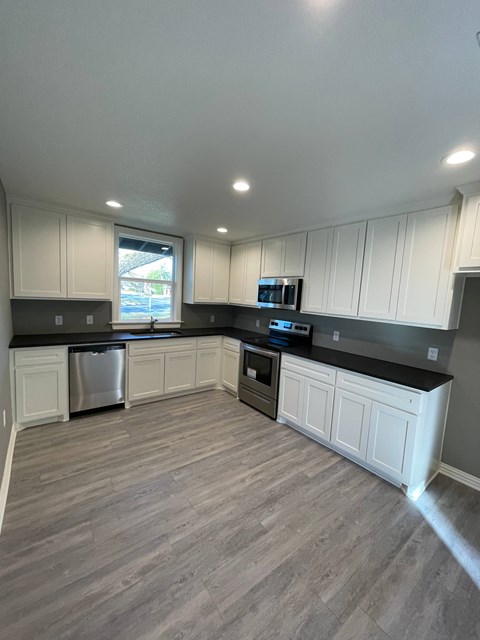 A kitchen with white cabinets and a grey floor.