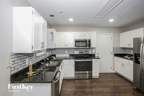A kitchen with white cabinets and a black counter top.
