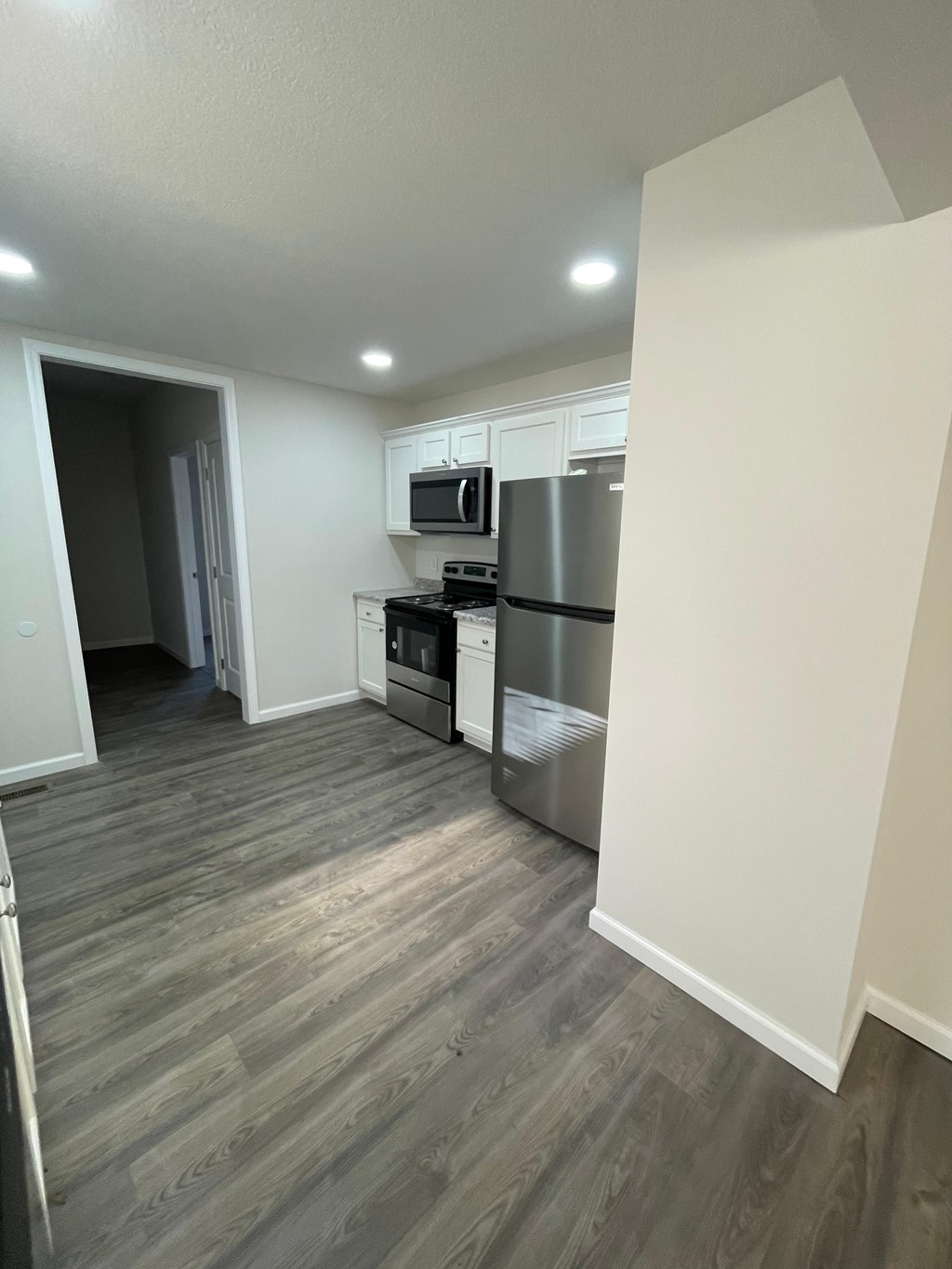 A kitchen with a refrigerator, oven, and microwave.