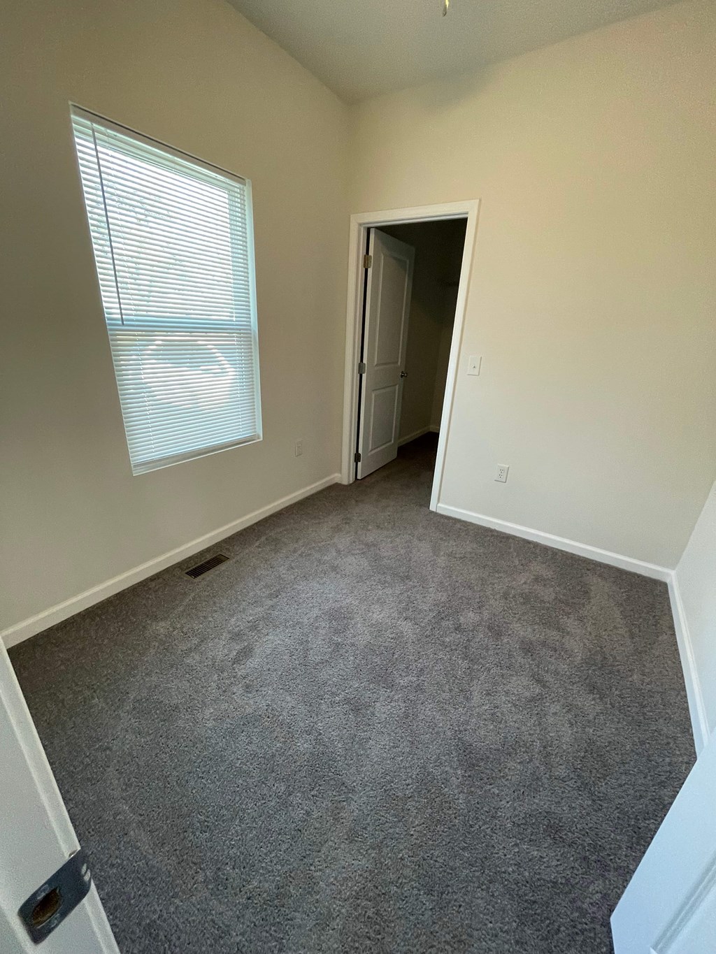 A room with a carpeted floor and a window with blinds.