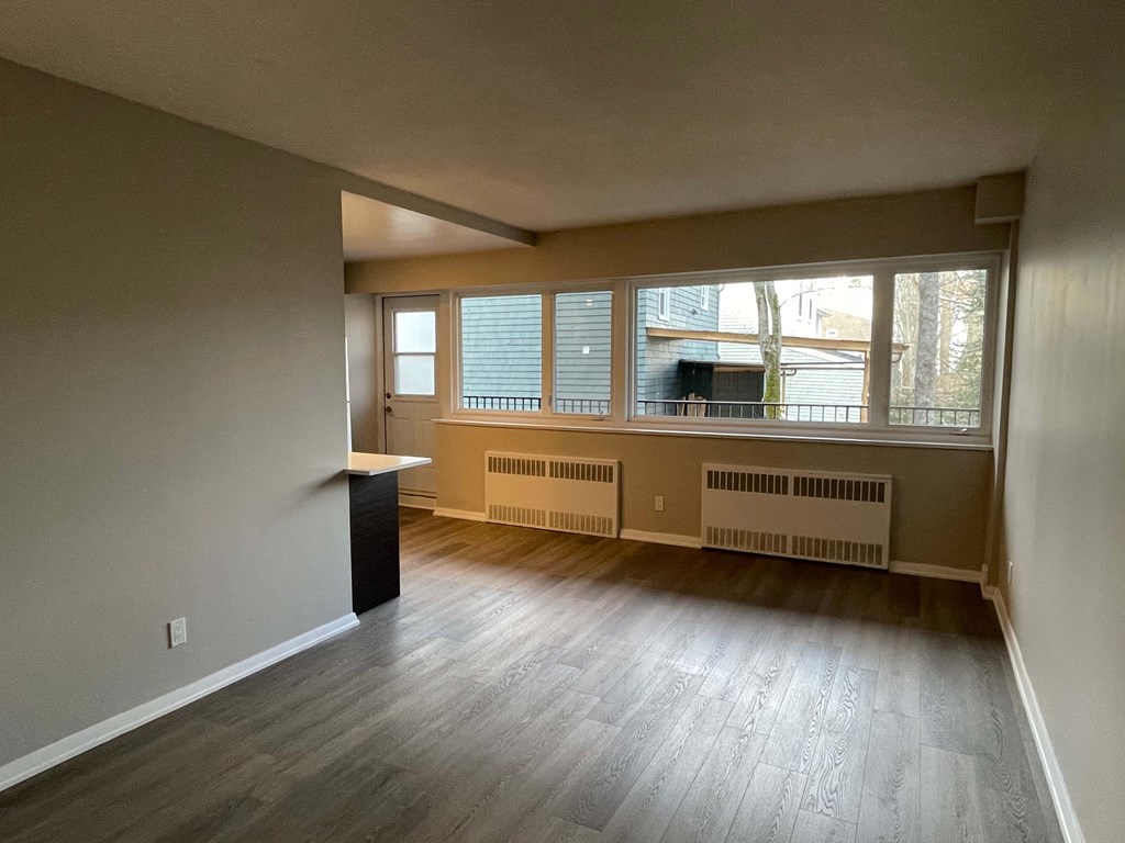 A room with a wooden floor and a window with blinds.