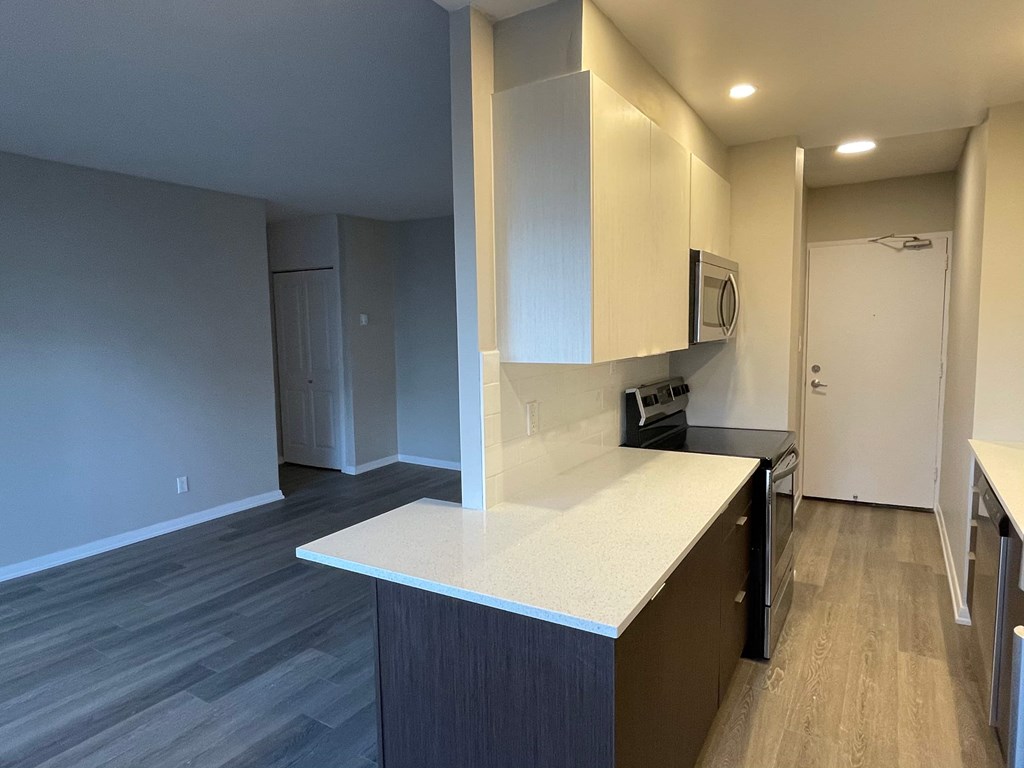 A kitchen with a white counter top and wooden cabinets.