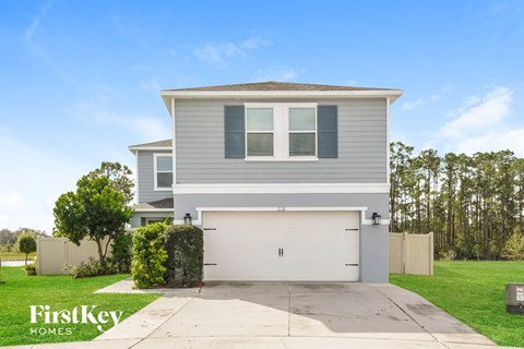a gray house with a white garage door and a lawn